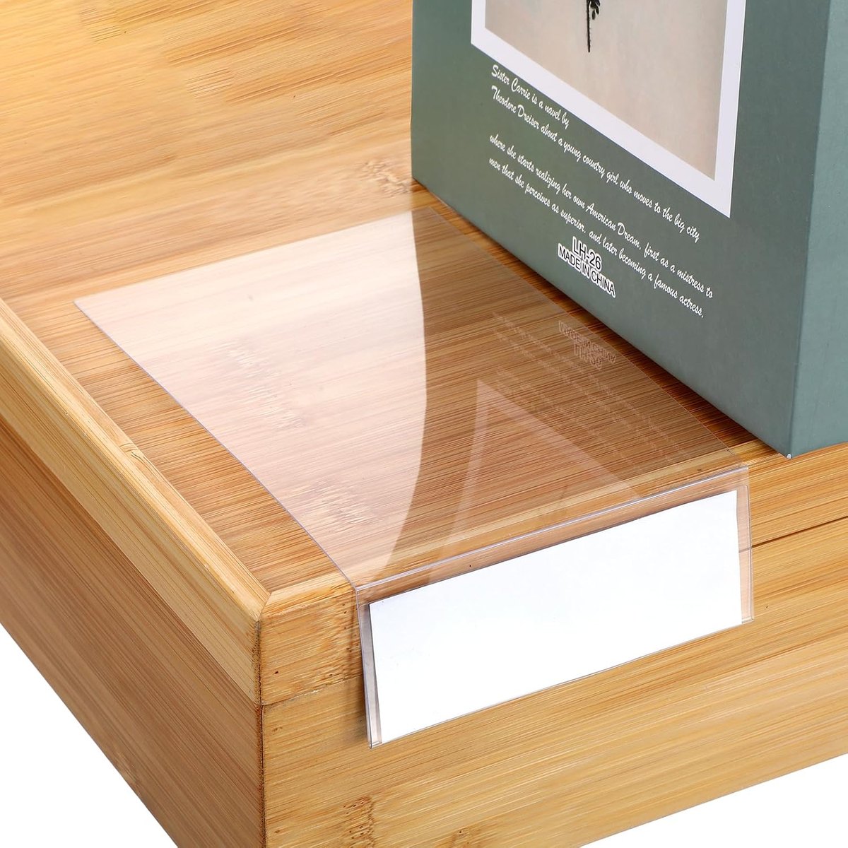 Clear moveable shelf marker sheet with a folded label tab on a shelf edge