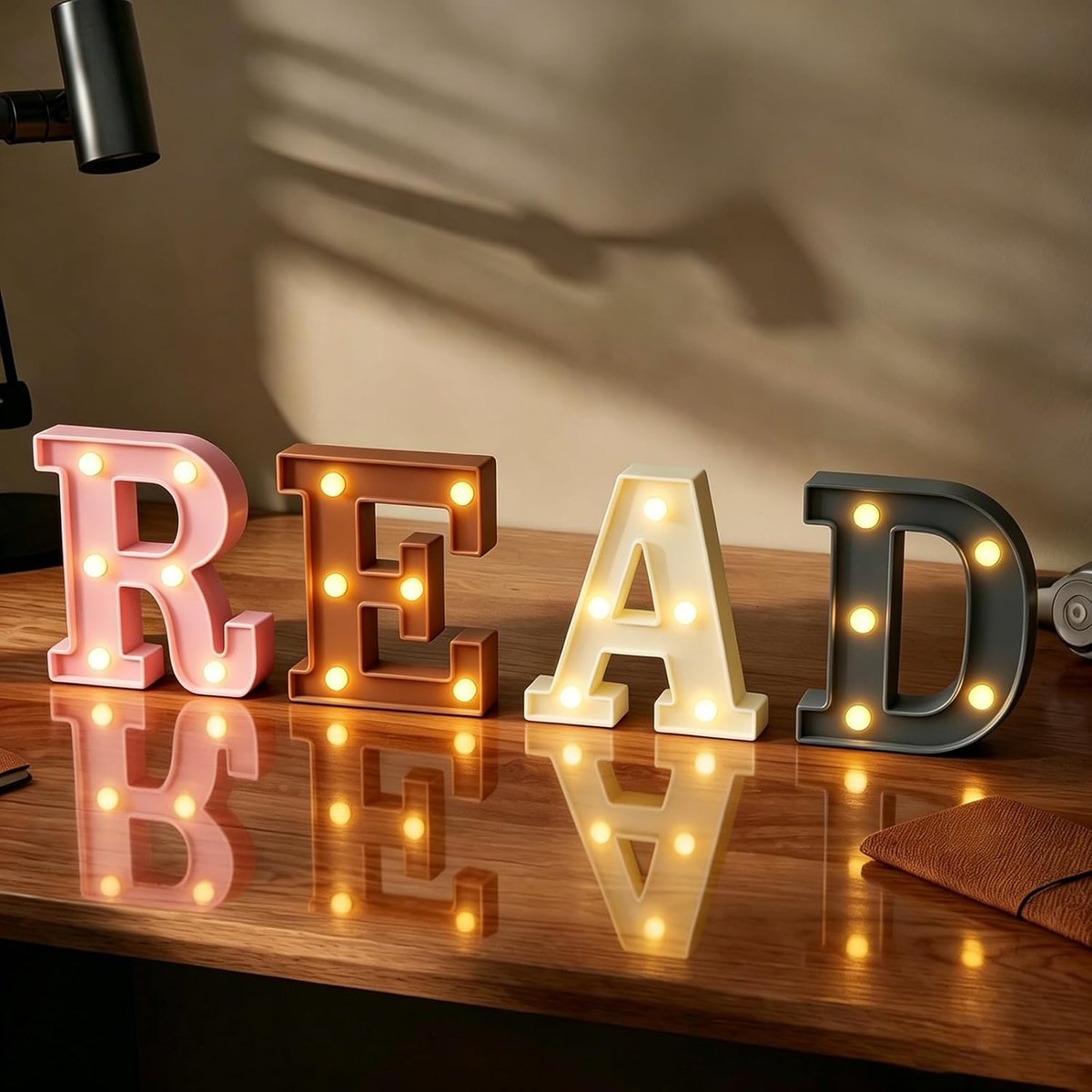 Marquee letters spelling READ in pink, terracotta, cream and charcoal, lit