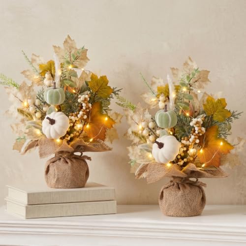 Two burlap-wrapped arrangements of cream leaves, white pumpkins and berry sprigs with warm lights threaded through