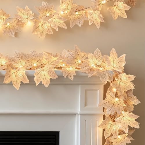Pale gold maple leaf garland with warm LED lights woven through, draped along a mantel
