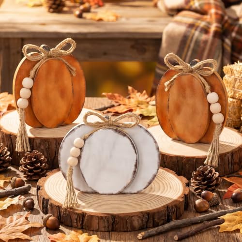 Rounded wooden pumpkin standing signs in orange and white with jute bows and wooden bead tassels