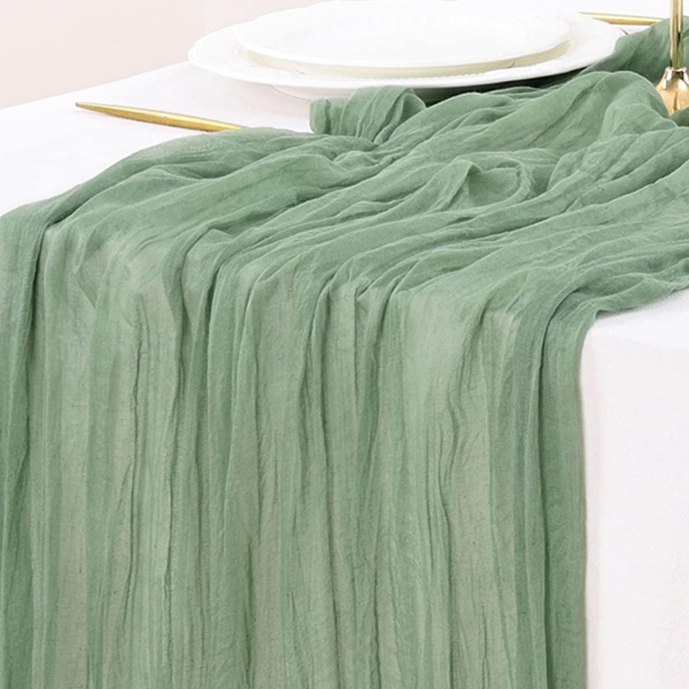 Sage green gauze cheesecloth table runner bunched along a table