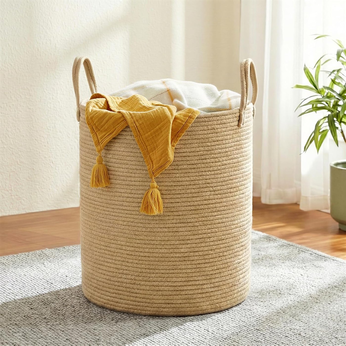 Tall woven cotton rope basket with handles holding folded blankets