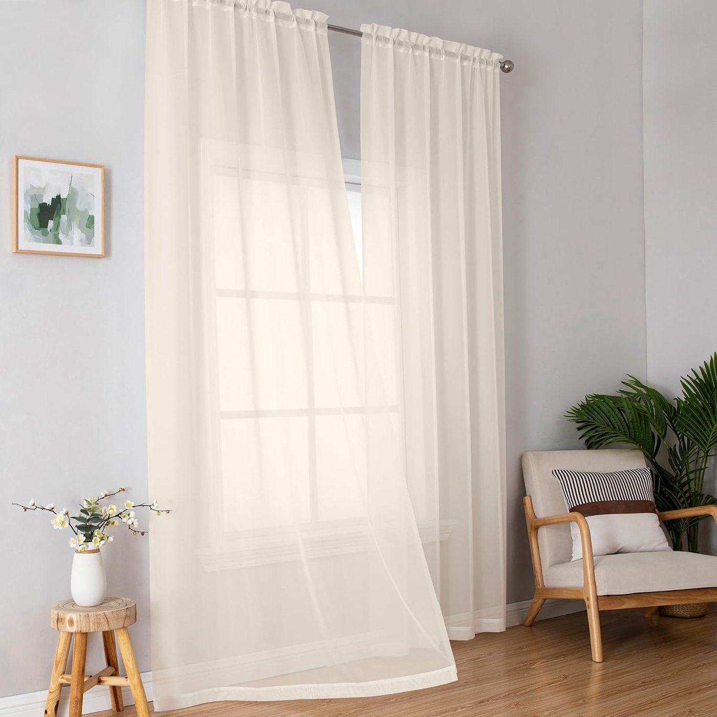 Cream sheer curtain panels filtering light at a tall window