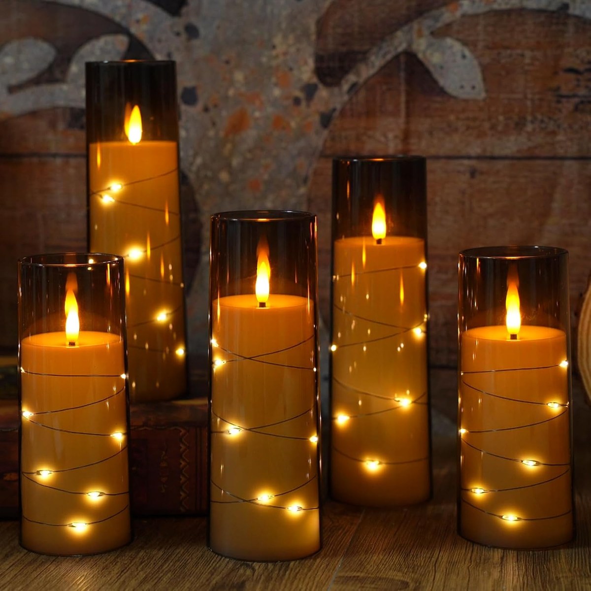Set of battery pillar candles in smoked glass sleeves with fine star string lights inside