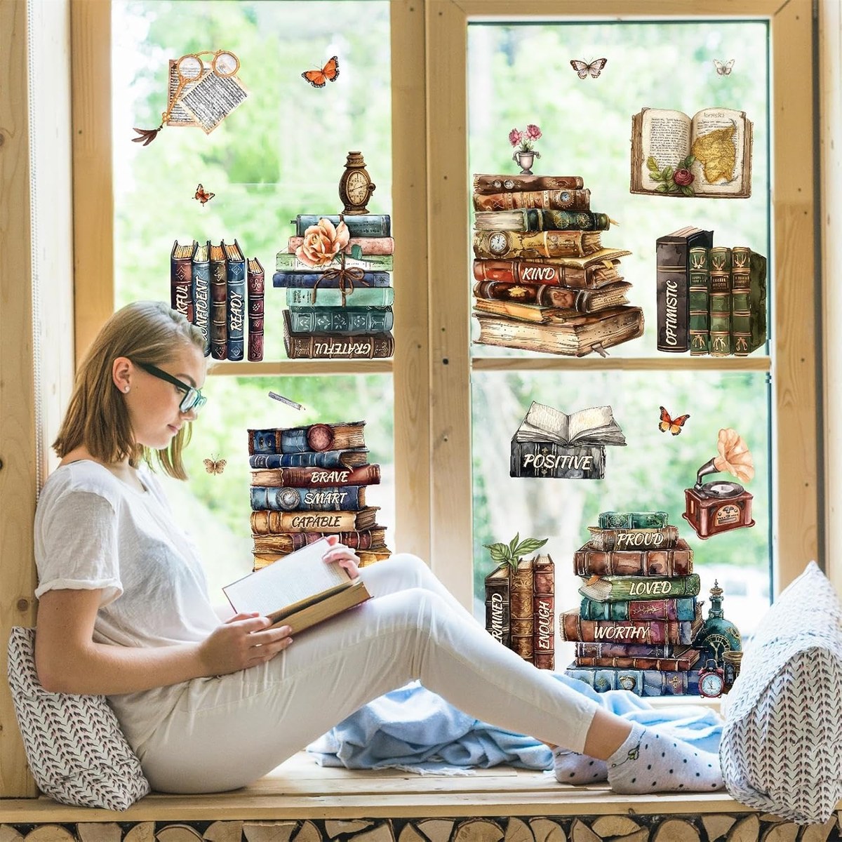 Window clings of watercolor antique book stacks and butterflies applied to a bright window